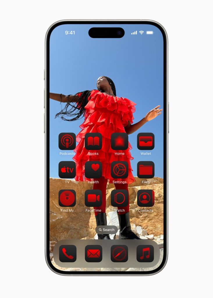 An official press image by Apple highlighting a new feature in iOS 18 and iPadOS 18, allowing users to select custom colors for their app icons in the Home Screen. The illustrated image shows a Home Screen wallpaper of black woman dressed in red, displayed on the back of an array of app icons that are tinted to become red foreground behind a back background. Note that these colors do not meet the global digital accessibility standards such as the Web Content Accessibility Guidelines (WCAG), requiring a minimum color contrast ratio to be considered legible for people with visual impairment.